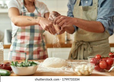 Cropped Shot Of Couple Preparing The Dough Together. Young Man And Woman In Apron Cooking, Making Pizza At Home. Hobby, Lifestyle. Focus On Hands. Horizontal Shot