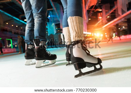 cropped shot of couple in skates ice skating on rink