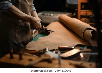 Cropped shot of a craftsman cutting a large piece of leather with precision scissors in his workshop. - Powered by Shutterstock