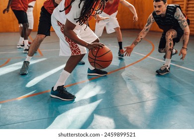 Cropped shot of a diverse professional players playing basketball in a sports hall while having a practice or a match. Focus on an african man with dreadlocks dribbling a ball. Copy space. - Powered by Shutterstock