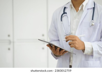 Cropped shot of a doctor using a digital tablet. Close up of doctor hands using digital tablet at clinic. Closeup of doctor in labcoat and stethoscope holding digital tablet. 
 - Powered by Shutterstock