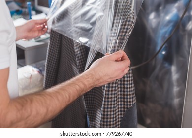 Cropped Shot Of Dry Cleaning Worker Packing Jacket In Plastic Bag