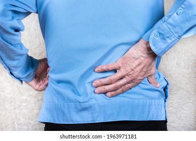 Cropped shot of elderly man hand holding lower back, suffering from backache. White background