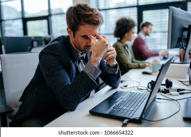 Cropped shot of a exhausted businessman sitting in front of his laptop computer in an office