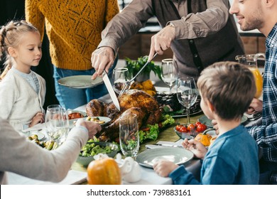 Cropped Shot Of Family Cutting Thanksgiving Turkey While Celebrating