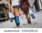 Cropped shot of female friends out for shopping in the city. Close up photo of female women legs walking while buying clothes presents for Christmas or on black friday.