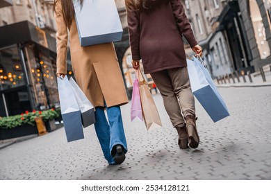 Cropped shot of female friends out for shopping in the city. Close up photo of female women legs walking while buying clothes presents for Christmas or on black friday. - Powered by Shutterstock