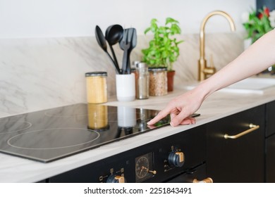 cropped shot of female hand press sensor button and using electrical hob for cooking dinner at home kitchen with stylish interior, modern household appliances concept - Shutterstock ID 2251843491