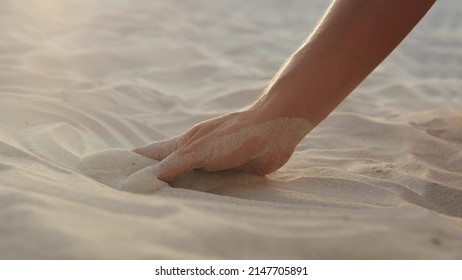 Cropped shot of female hand touching sand on beach - Powered by Shutterstock