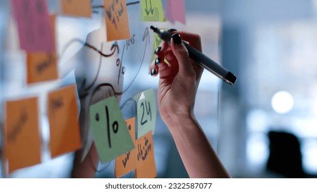 Cropped shot of female hand writing on glass board with colorful sticky notes. Brainstorm, strategy and business concept - Powered by Shutterstock