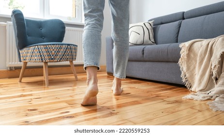 cropped shot of female legs walk barefoot on wooden warm floor near couch in living room at home, heating concept - Powered by Shutterstock