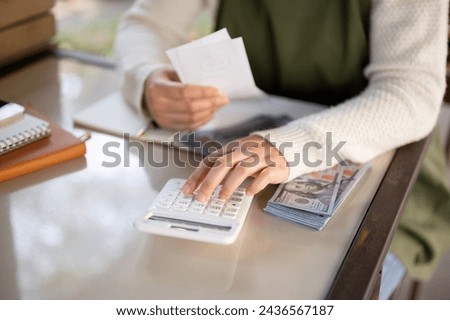 A cropped shot of a female small business owner using a calculator, calculating bills, planning her shop expenses, and counting her daily sales.