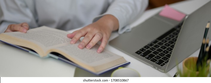 Cropped Shot Of Female University Student Looking For Informations On Book For Her Thesis