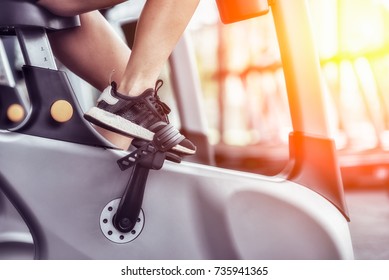 Cropped Shot Of Fitness Woman Working Out On Exercise Bike At The Gym. Female Exercising On Bicycle In Health Club, Focus On Legs.
