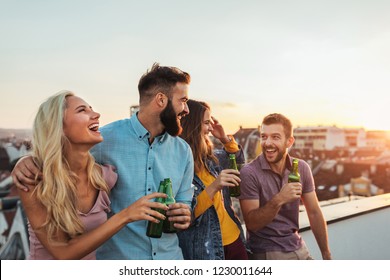 Cropped shot of four friends hanging out on a rooftop - Shutterstock ID 1230011644