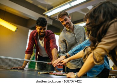 Cropped Shot Of Four Friends Stacking Hands On Top Of Each Other Above The Ping Pong Table