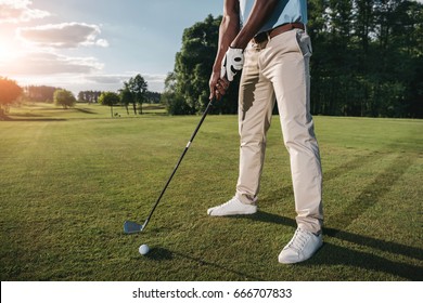 Cropped shot of golfer holding club and hitting ball on green grass - Powered by Shutterstock