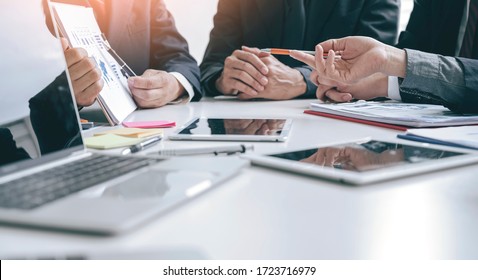 Cropped shot group of businesspeople using graph chart and computer laptop, tablet discussing about business plan together in modern office. - Powered by Shutterstock