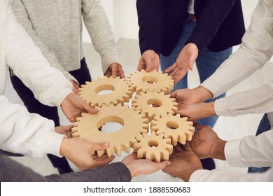 Cropped Shot Of Group Of Multiethnic People Joining Gear Wheels Together As Metaphor For Team Collaboration, Unity, Teamwork, Finding Creative Solutions And Creating Well-functioning Business System