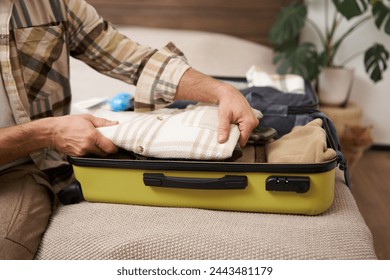 Cropped shot of hands packing clothes in luggage, going on vacation and prepared his suitcase, organises his items inside bag, packs for holiday. - Powered by Shutterstock