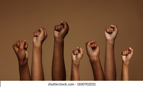 Cropped shot of hands raised with closed fists. Multiple hands raised up with closed fist symbolizing the black lives matter movement. - Shutterstock ID 1830702032