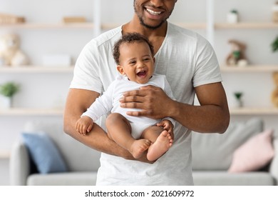Cropped Shot Of Happy Black Father Holding His Cute Little Laughing Baby While They Relaxing Together At Home, Adorable African American Infant Child Enjoying Spending Time With Daddy, Closeup