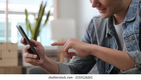 Cropped shot of happy man sitting on sofa at home and using smart phone.	 - Shutterstock ID 2155126261