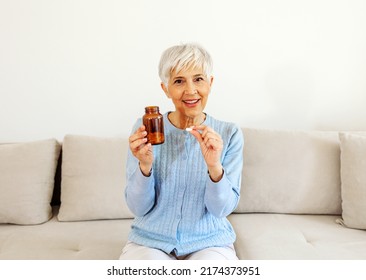 Cropped Shot Of Happy Senior Woman Taking Pills From Prescription Bottle On To Her Hand, Looking At Camera.