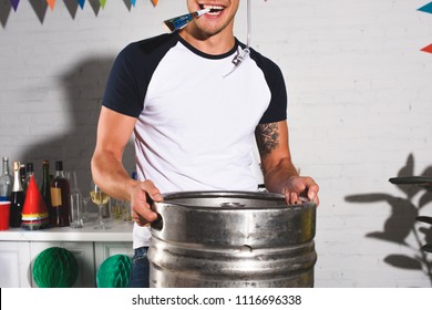 Cropped Shot Of Happy Young Man Holding Barrel Of Beer At Home Party