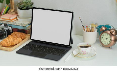 Cropped shot of home office with digital tablet, supplies, croissant and coffee, clipping path - Powered by Shutterstock