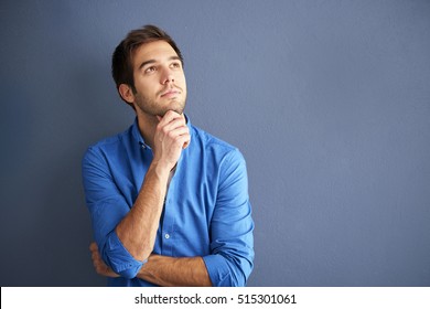 Cropped shot of a hopeful young man wearing casual clothes while standing in front of a grey wall.