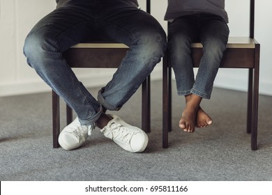 Cropped Shot Of Legs Of Father And Son Under Table