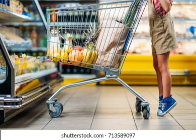 Cropped Shot Of Little Child Standing Near Shopping Cart At Grocery Shop