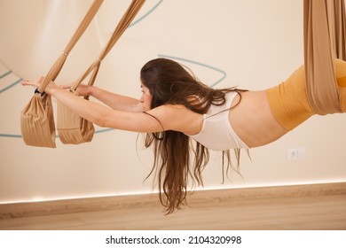 Cropped Shot Of A Long Haired Fit Woman Doing Superman Pose On Fly Yoga Hammock