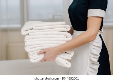 Cropped Shot Of Maid In Uniform Holding Stack Of Clean Towels In Hotel Suite