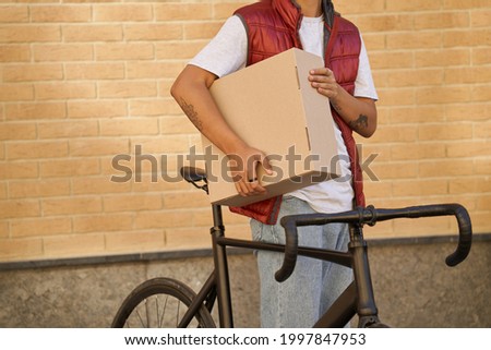 Cropped shot of a male courier holding parcel while standing wit