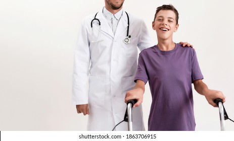 Cropped shot of male doctor helping teenaged disabled boy with cerebral palsy, taking steps using his walker isolated over white background. Children with disabilities and special needs. Web Banner - Shutterstock ID 1863706915