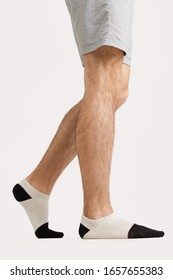 Cropped shot of male legs in gray cargo shorts and white cotton socks with black toes and heels. The photo is made on the white background.  