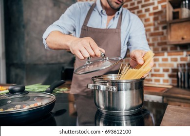 Cropped Shot Of Man With Apron Cooking Pasta