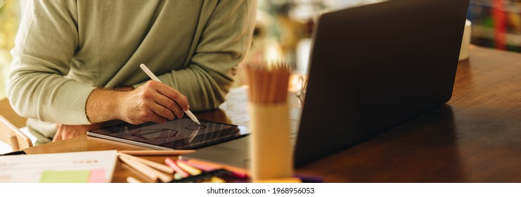 Cropped shot of a man drawing illustration on his graphic tablet. Artist using digital tablet to draw illustrations at home.