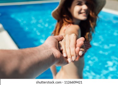 Cropped Shot Of Man Holding Hand Of His Happy Wife In Swimming Pool, Follow Me Concept