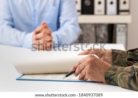 Cropped shot of a man and military man completing paperwork together at a desk