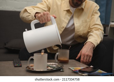 Cropped Shot Of A Man Pouring Hot Water From Electric Kettle Into His Cup