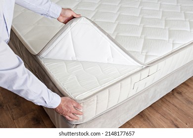 Cropped shot of man showcasing the waterproof topper for white orthopedic mattress. Male showing hypoallergenic foam matress protector. Close up, copy space, top view, background. - Shutterstock ID 2148177657