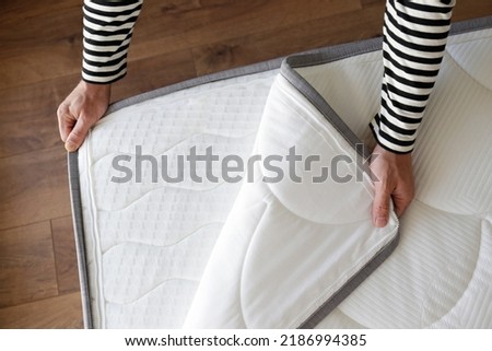 Cropped shot of man showcasing the waterproof topper for white orthopedic mattress. Male unzipping hypoallergenic foam matress protector. Close up, copy space, top view, background.