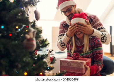  Cropped shot of a man surprising his girlfriend with a Christmas gift. - Powered by Shutterstock