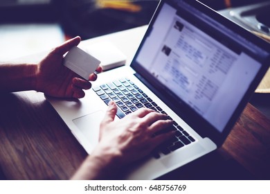 Cropped shot of a man's hands using a laptop at home while holding credit card in the hands, online shopping at home, cross process, filtered image - Shutterstock ID 648756769