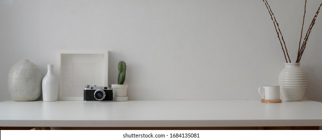 Cropped shot of minimal workspace with camera, decorations and copy space on white table with white wall 