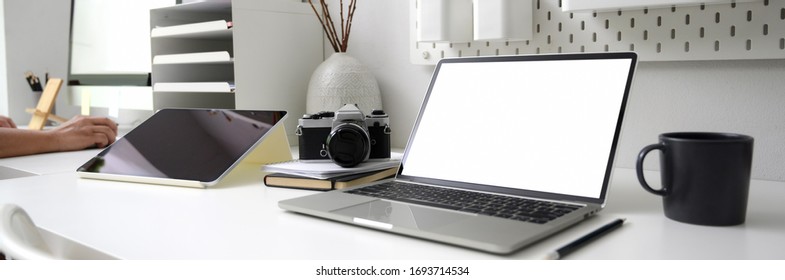 Cropped shot of modern office desk with blank screen laptop, office supplies and coffee mug on white table  - Powered by Shutterstock