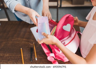 Cropped Shot Of Mother And Daughter Packing Stuff In Backpack For School